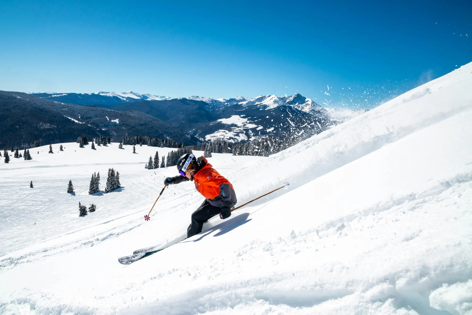 Skier carving fresh powder under a blue sky